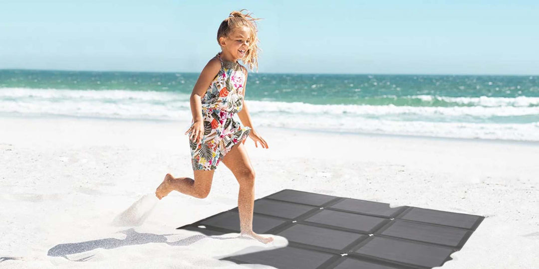 Ein Mädchen, das am Strand auf das faltbare Solarmodul von BougeRV tritt